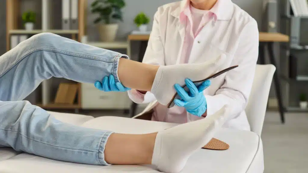 Doctor examining a patient’s foot for metatarsalgia and assessing pressure points in the ball of the foot during a podiatry consultation